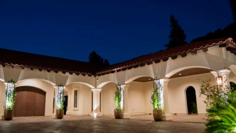 A courtyard view of a mansion, contrasting against the evening sky due to home accent lighting