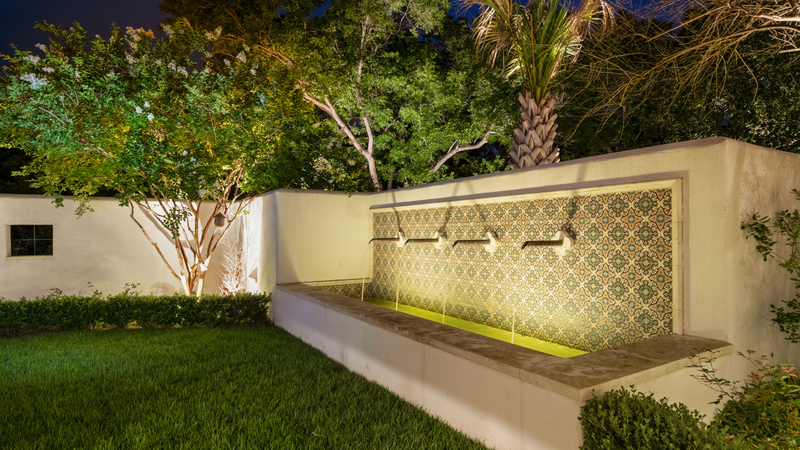 Lush green garden with white-colored borders, lit under the evening sky by led landscape lighting