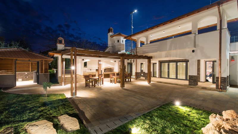 A wide frame capture of a mansion shining bright against the night sky due to lighting installation