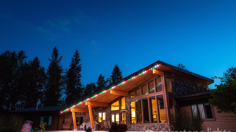 Modern house adorned with permanent red and green holiday lights along the roofline